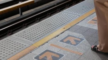 Yolcu ayağının görüntüsü ile SkyTrain İstasyonu platformunun alçak açılı görüntüsü ile kalabalık bir saatte gökdelene binmek ve tren istasyonuna, thailand toplu taşıma sistemine ulaşan banliyö treni
