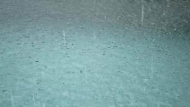 Yüzme havuzunda suyun yüzeyine bakan yağmur damlacıkları yaz mevsiminde havuz kenarındaki özel havuza düşer, doğal yağmur arka planda kalır.