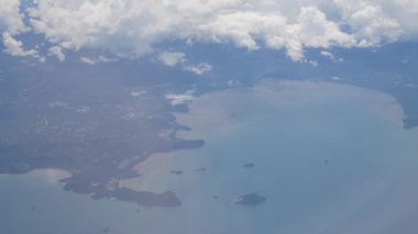 Güneşli bir günde, deniz kıyısındaki adanın üzerinde bulutların üzerinde uçarken hava mavi gökyüzü manzarası seyahat tatil seyahati arka planı.