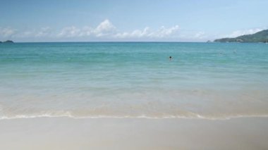 Güneşli bir öğleden sonra deniz kıyısı üzerinde doğal manzara. Deniz dalgaları beyaz kumsala vuruyor. Dalgalar pürüzsüz beyaz kumsal manzarasına çarpıyor..