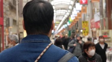 POV, Osaka 'da yürürken kot ceket giyen Asyalı bir adamı takip ediyor. Gün içinde alışveriş caddesinde yürüyor, sokak hayatı yerel alışveriş caddesinde.