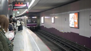 Şubat 1.2024.Osaka, Japonya. Japonya 'da kalabalık bir metro peronunda tren tam zamanında gelecek olan insanlar bekliyor. Video şehir yaşamını, verimliliği ve Osaka şehrinin ritmini yansıtıyor.