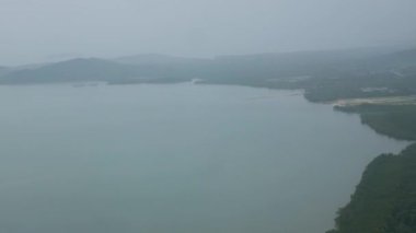 Gökyüzünde, okyanusun üstünde uçan uçak penceresinden yağmurlu bir günde havaalanına inişe yaklaşan bulutlu hava manzarası, uçak penceresinden tatil arka planındaki manzarayı görmek.