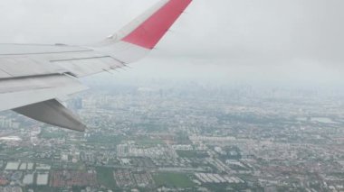 Gökyüzünde, Bangkok şehrinin silueti ile yüzen beyaz, kalın bulutlara doğru uçan kanat manzaralı uçak bulutları arasında uçan uçak ulaşımı