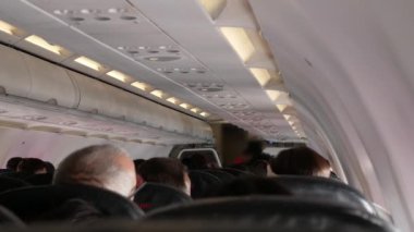Uçak yolcularla dolu bir şekilde gökyüzüne tırmanırken uçaktaki koridor geçidine ve uçaktaki koltuklara bakın.