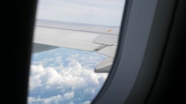 Bulutların üzerinde bulutların üzerinde uçarken bulutların üzerinden bulutların üzerinden geçen, bulutların hareket ettiği, yaz tatili arka planında uçağın mavi gökyüzü üzerindeki kanadı ile birlikte uçağın penceresinden bakmak.