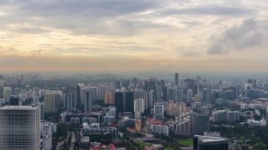 Günbatımında Singapur şehrinin gökyüzü manzarası gökdelenler, binalar ve bulutlar gökyüzünde hareket ediyor.