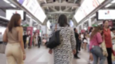 Trenin yoğun saatinde yolcu değiştiren kalabalık Skytrain istasyonu platformunda odak dışında istasyondan gelen ve giden hava treni, toplu taşıma arkaplanı