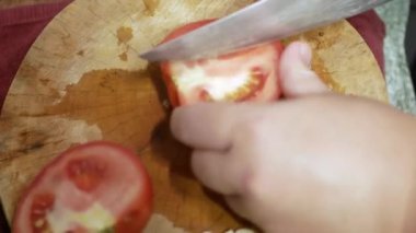 Elinizi seçici bir şekilde kapayın. Taze kırmızı domatesi ahşap kesme tahtasıyla dilimleyin. Yemek pişirmeye hazır olun.