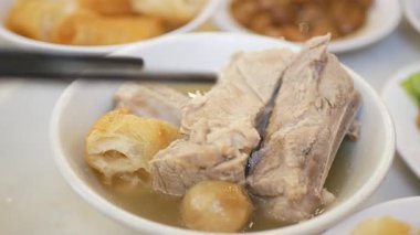 Yemek saatinde bir kase bak kut teh 'den domuz kaburgası kapmak için yemek çubukları kullanırdım. Asya Singapur Malezya usulü sıcak çorba. Gelenek kültürü Asya tekil yiyecekleri