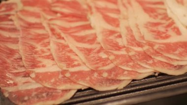 Japon usulü restoranda Shabu shabu sosu pişirmek için tepside dilimlenmiş ete odaklanmış seçici bir bakış açısıyla yaklaşın.
