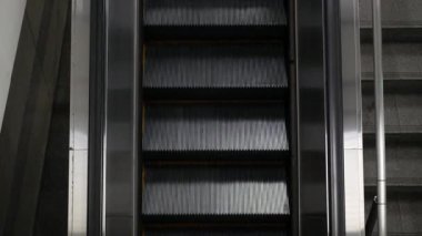 Metro istasyonundaki ya da havaalanındaki merdivenlere yukarıdan bakıldığında başka bir kata giden bir yolcu, toplu taşımacılık, ulaşım ve iş konsepti...