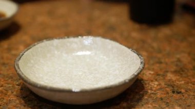 Japon restoranında Japon yemeği daldırmak için Shoyu soya sosu dökerken seramik tabağa seçici bir şekilde odaklan. Geleneksel Japon restoranı.