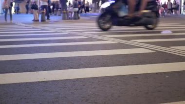 Tayvan 'ın başkenti Taipei' de gece vakti şehir merkezindeki zebra geçidi bölgesine düşük açıyla odaklanırken, arabalar ve mmotorike yeşil ışıkta hızla ilerlerken, yaya caddeyi geçmek için bekliyor.