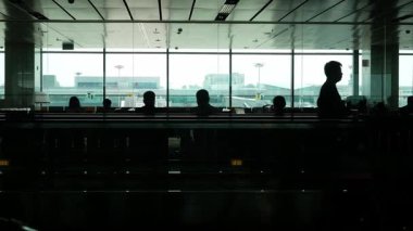 Ağustos 2,2023. Cingapore Changi Havaalanı. Yolcular hareket halindeki yürüyen yürüyen merdivende, silüet içinde Singapur Havaalanı 'nda uçuş bekleyen birçok yolcuyla birlikte yürüyorlar.