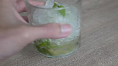 Boş bardak buzlu mojito kokteyli, limon ve nane yapraklı alkolü kafenin ahşap masasına koyun.