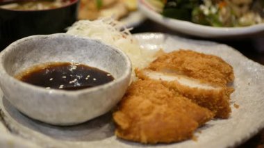 Bir tabak kızarmış domuz ya da tonkatsu 'ya odaklanın. Japon yemeği yerken eliniz yemek çubuğuyla bir tabak kızarmış domuzu lokantada yemek saatinde tabaktan alır.