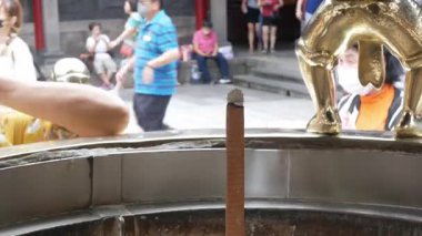 Çin mimarisinin ünlü mabedi Taipei 'de insanların inançla dua ettiği ve joss çubuklarının etrafında fetişlerini aktifleştirdiği dev bir tütsü tenceresine bakın.