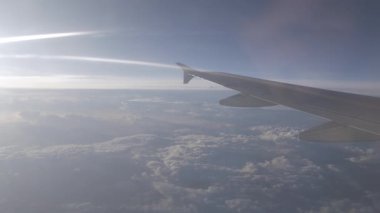 Gün batımında bulutların üzerinde gökyüzüne tırmanırken uçağın penceresinden dışarı zoom yap, doğal ulaşım tatil arka planı.
