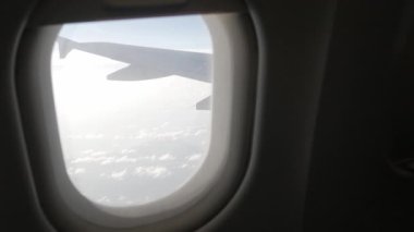Gün batımında bulutların üzerinde gökyüzüne tırmanırken uçağın içeriden pencereyi seyretmek, doğal ulaşım tatil arka planı.
