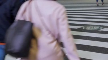 Tokyo 'daki Shinjuku alışveriş caddesinden geçen yaya kalabalığı kışın Japonya' da yürürken, zebra kavşağındaki asfalt sokağa alçak açılı görüş.