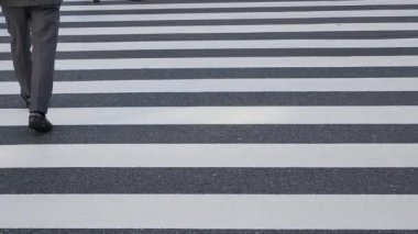 low angle view to the asphalt street at zebra crossing area at intersection while crowded of people pedestrian walking crossing ginza shopping street in Tokyo city of japan in winter day time