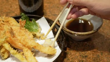 Bir tabak çıtır karides, temupra Japon yemeğine odaklanın. Elleriniz yemek çubuğuyla öğle yemeği zamanında tempura 'yı bir tabaktan alır. Kızarmış Japon karidesleri.