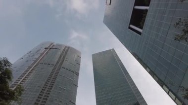 Şehir ticaret bölgesindeki modern ofis gökdelenleri finans binaları. Arka planda açık gökyüzü ile gökyüzüne yükselen modern cam binalara bakarken yukarı bakıyorum.