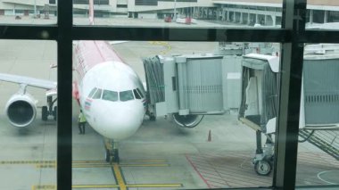 Varış uçağı havaalanının giriş kapısına park ederken yaz tatilinde uluslararası havaalanı hizmetleri. Havaalanı yer operasyonu