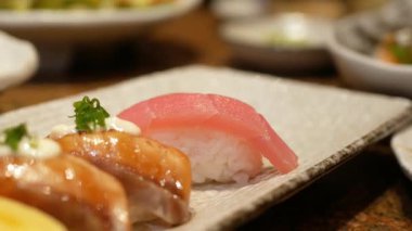 Öğle yemeği saatinde yemek çubuğuyla bir tabak suşiyle Japon yemeği yemeye odaklan. Yemek saatinde yemek çubuğuyla suşiyi tabaktan al. Modern geleneksel Japon yemekleri..