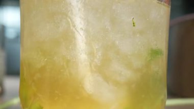 Bir bardak mojito kokteyline odaklan limon ve nane yapraklı alkol içerken yakın plan içmek için pipet kullan, kokteyl iç.