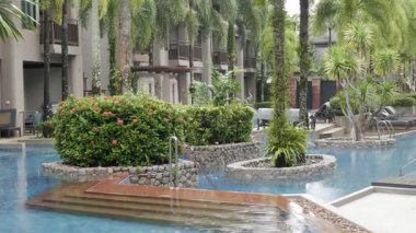 30 Eylül 2022 Phangnga, Tayland. Modern tasarım merkezindeki tropikal ağaçlarla dolu ılık, rahatlatıcı yüzme havuzunun manzarası kasvetli hava zamanıyla