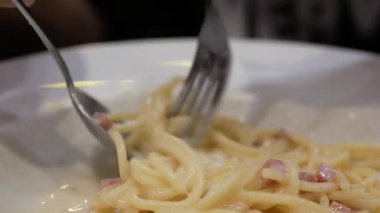 Akşam yemeği için ev yapımı spagetti beyaz soslu makarna yemek için çatal ve kaşık kullanmak, İtalyan mutfağı ev yapımı yemek yemek, kabaralı beyaz soslu makarna yemek.