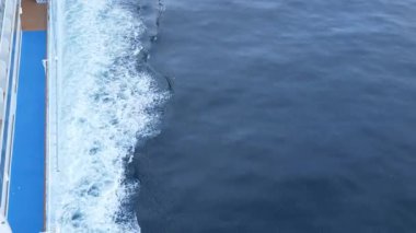 Yolcu yolcu gemisinin yan tarafındaki su yüzeyinde dalgalanan dalgalara bakın. Gündüz okyanusta seyahat ederken, su dönerken, deniz yüzeyinde dalgalanan dalgalar.