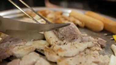 Kore usulü ızgara domuz eti pişirirken yakın çekim ve ızgarada et kesmek için makas kullanın. Izgarada domuz göbeği, tavada domuz eti pişirme, Kore usulü barbekü.