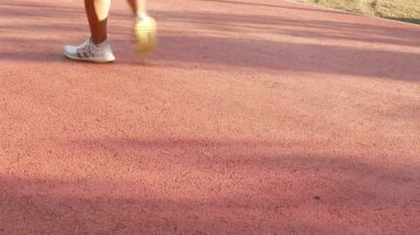 Parktaki koşu parkuruna bak. İnsanlar yürüyüş yapıyor ya da koşuyor. Güneş ışığıyla, spor arka planlarıyla.