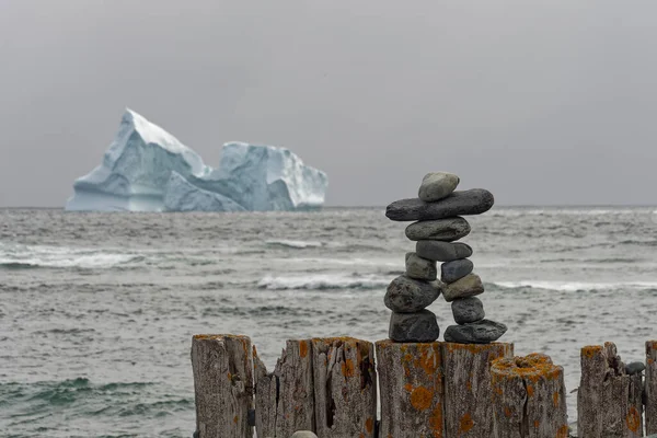 背後に大きな氷山がある古い木造の防波堤に構築されたInuksuk — ストック写真