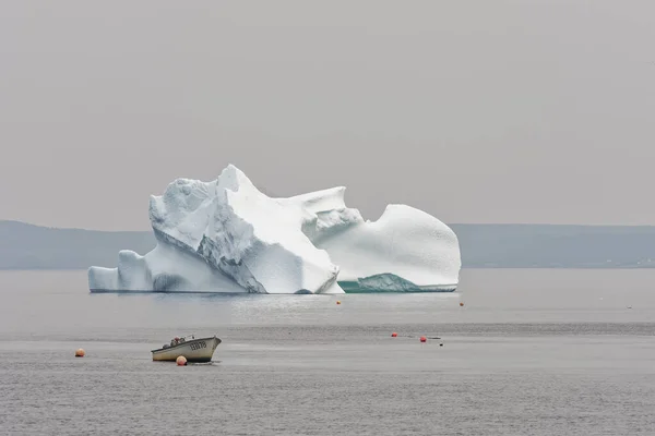 2023年6月23日 一艘渔船在加拿大纽芬兰和拉布拉多国王湾的一个阴霾的日子停在冰山边 — 图库照片