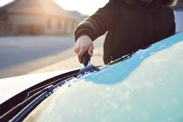 在一个寒冷的冬日早晨 一个男人刮伤了他汽车的前窗 图库图片