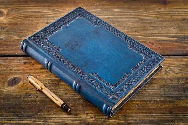 Süslemeli antik mavi deri kitap ahşap masaya serildi.