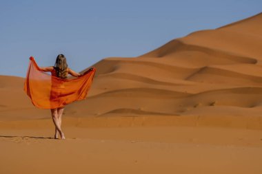 Güzel bir model, Fas 'taki büyük Sahra Çölü' ndeki kum tepelerine çıplak poz veriyor.