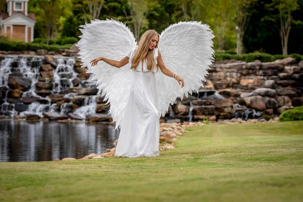 stock image A gorgeous blonde model poses outdoors while while wearing a set of white wings for halloween. 