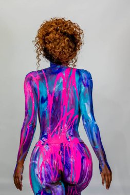 Göz kamaştırıcı bir kadın modeli, stüdyo ortamında canlı renklerle boyanır.