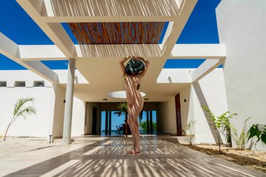 Muhteşem çıplak Latin bir model bambu tavanın altında poz veriyor, fayans zeminde güzel şekiller yapıyor..