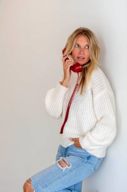 A gorgeous blonde model talks on the phone showing emotion in a home environment