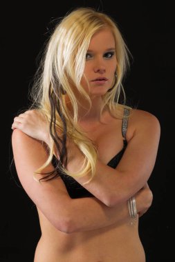 Çekici sarışın bir iç çamaşırı modeli stüdyo ortamında poz veriyor.