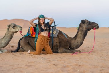 Güzel bir model Fas 'taki Sahra Çölü' nde deve sürüyor.