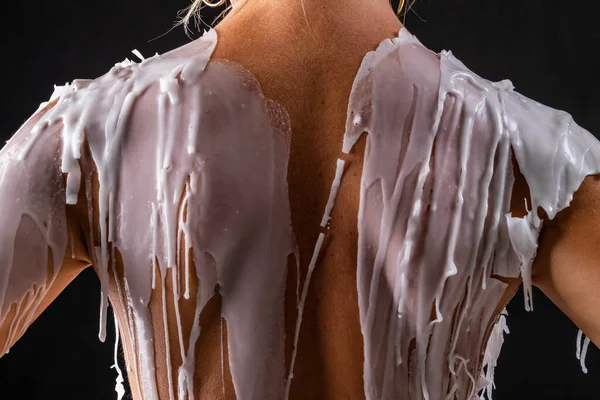 Çekici sarışın bir fetiş modeli, stüdyo ortamında vücuduna sıcak mum sürerken çıplak poz veriyor. 