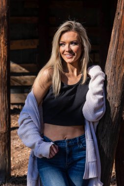 A gorgeous blonde cowgirl model poses outdoors while enjoying the spring weather