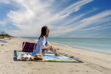 Güzel sarışın bir bikini mankeni sahilde açık havanın tadını çıkarıyor.